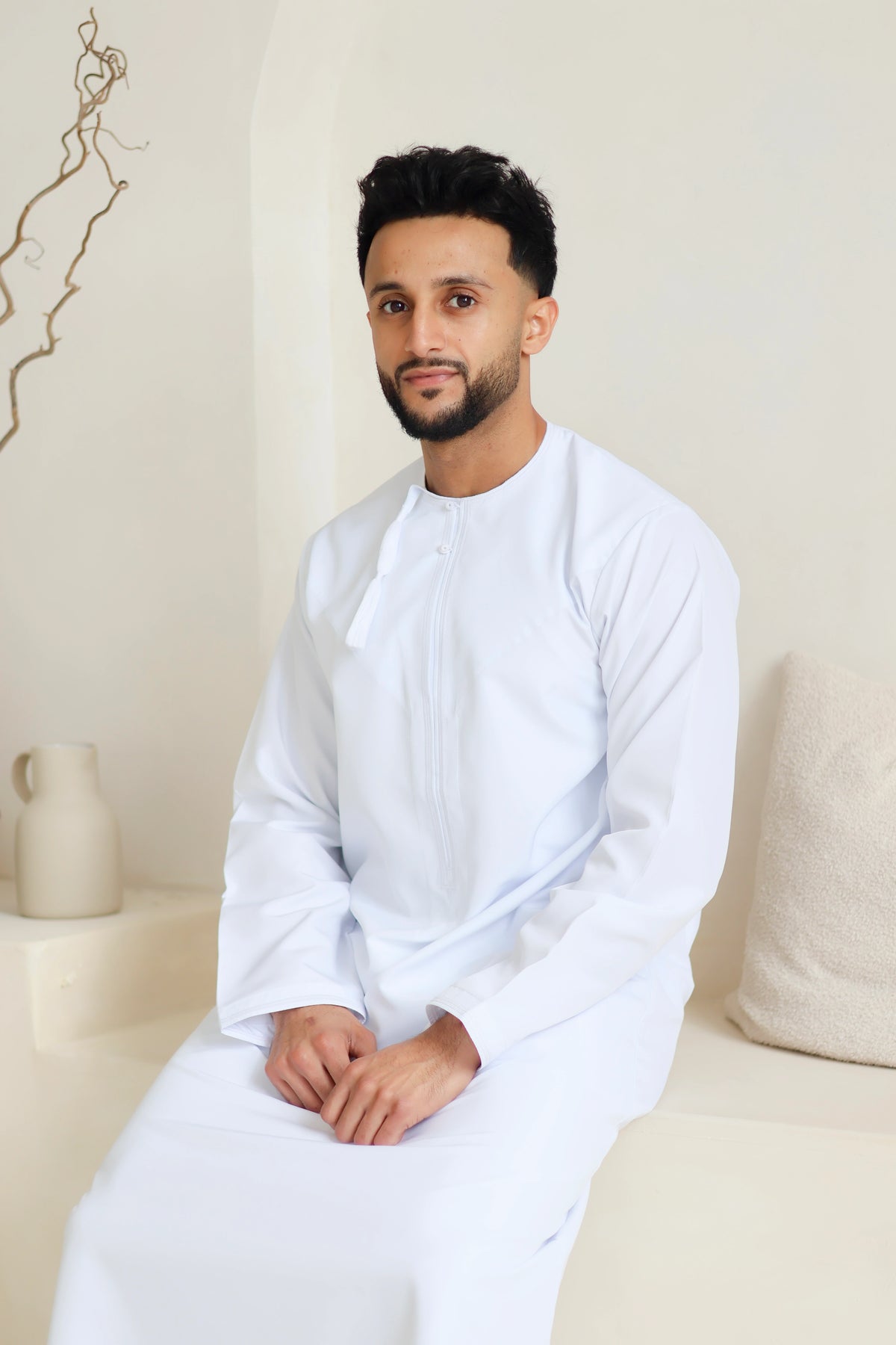 Men’s white Omani thobe seated lifestyle view – Qalbi