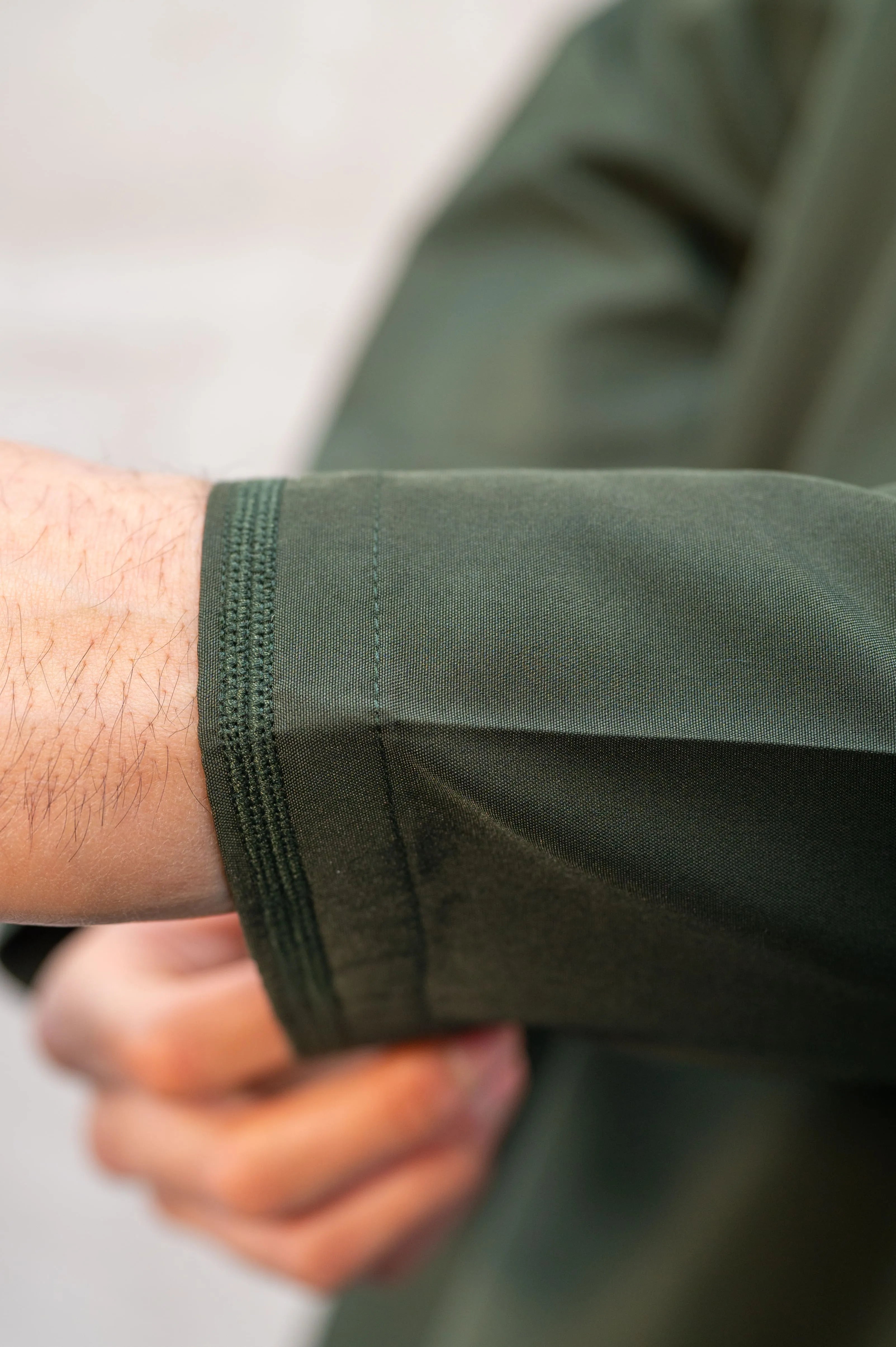 Close-up of intricate sleeve embroidery on premium forest green / Olive green Omani thobe/jubba, showcasing artisan craftsmanship and fine detailing