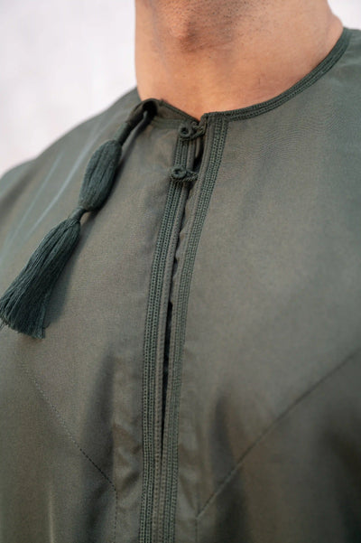 Detailed close-up of chest embroidery and tassel on forest green / Olive green Omani thobe/jubba, showcasing intricate hand-stitched design and heritage craftsmanship