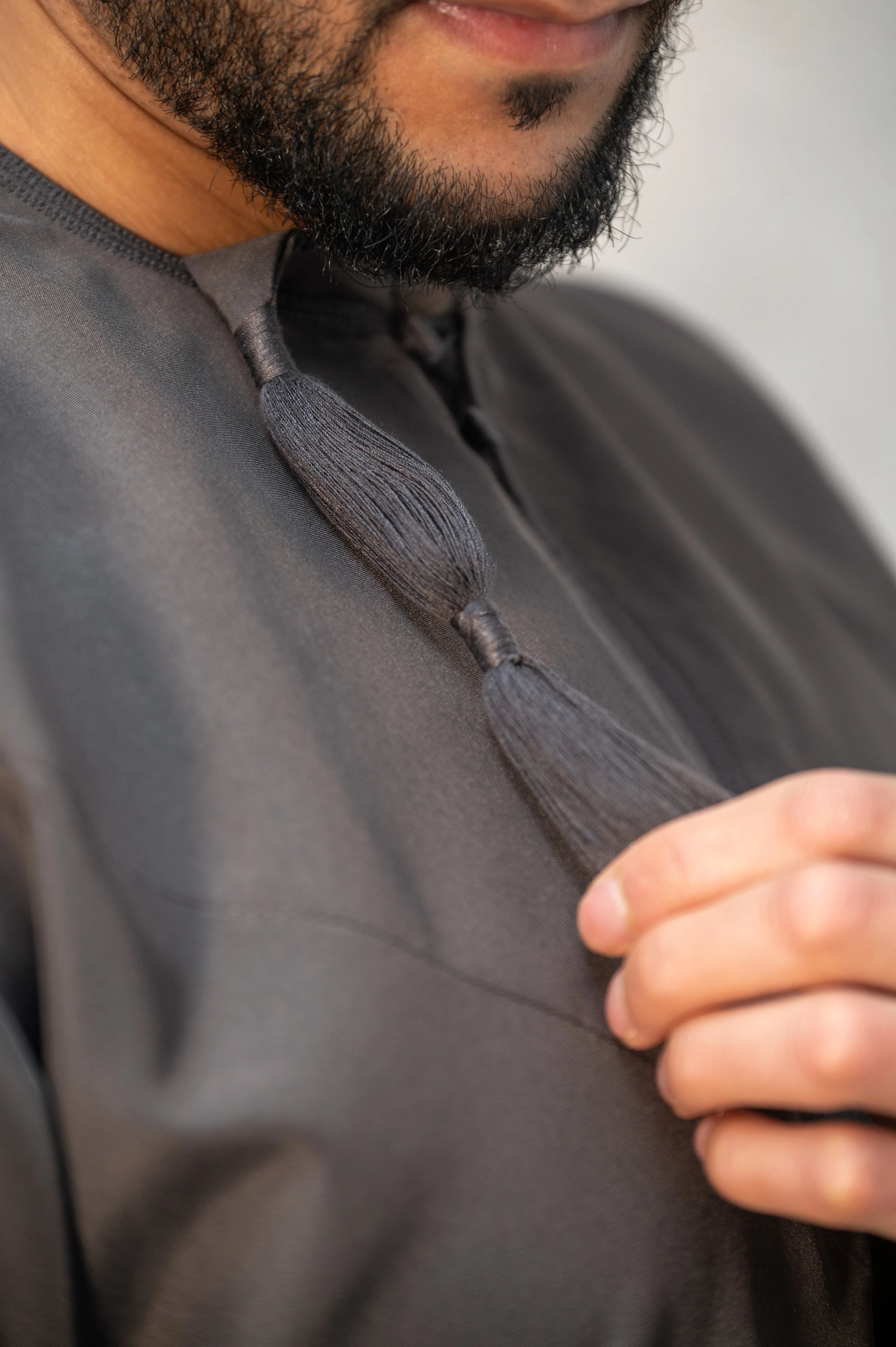 Close-up of grey Omani thobe / jubba tassel, hand-finished with reinforced stitching for added durability and refined craftsmanship