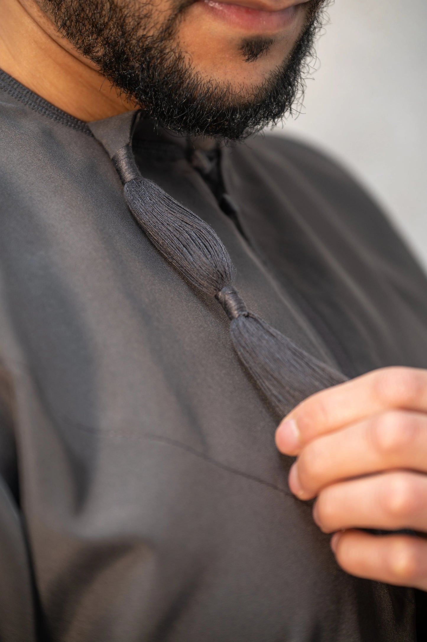 Close-up of grey Omani thobe / jubba tassel, hand-finished with reinforced stitching for added durability and refined craftsmanship