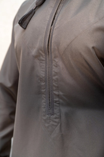 Close-up of chest embroidery and tassel on grey Omani thobe / jubba featuring detailed stitching and authentic handcrafted elements