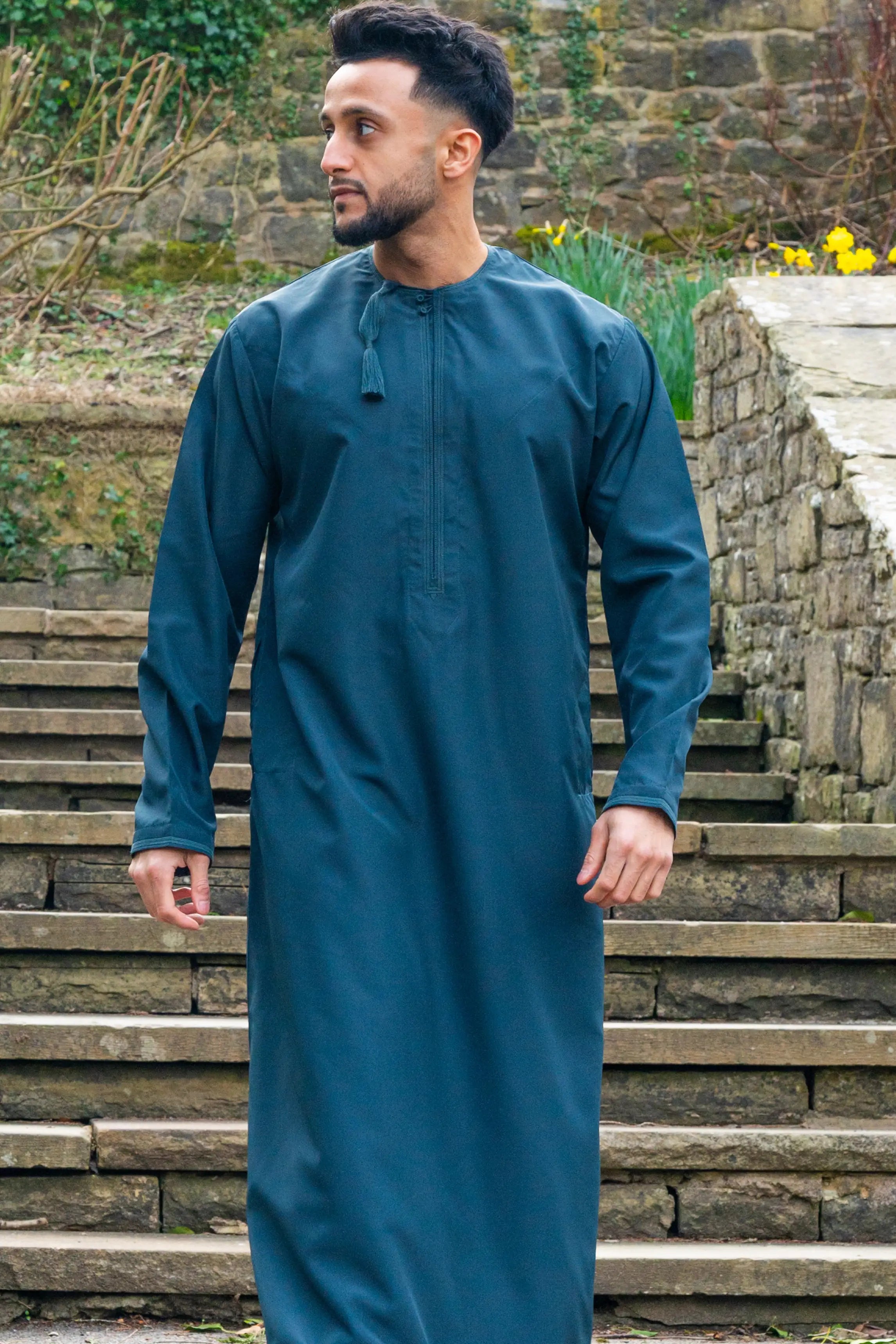 Omani Thobe / Jubba in teal blue shown in natural lighting outdoor
